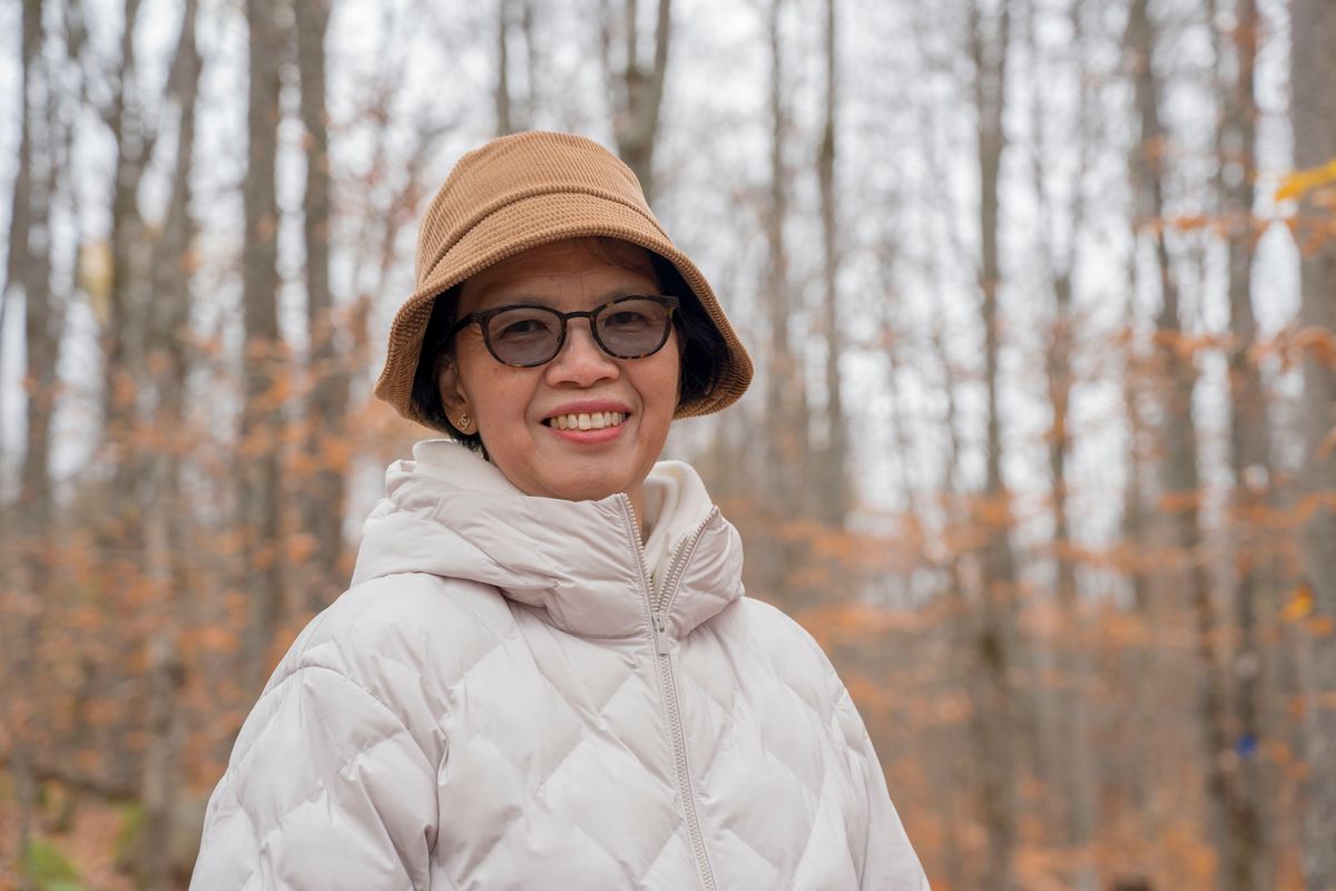 A smiling woman in an autumn forest, representing Thrive's Well-being area